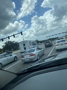 cars and trucks are stopped at an intersection on a cloudy day with traffic lights in the foreground