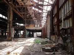 an abandoned warehouse with lots of windows and rusted metal structures on the floor,