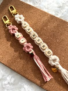 two lanyards with letters and tassels attached to them