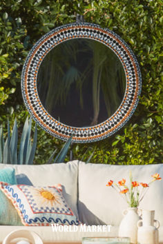 a couch sitting in front of a mirror on top of a wooden table next to plants