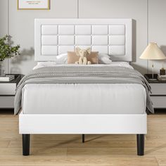 a white bed sitting on top of a hard wood floor next to a night stand