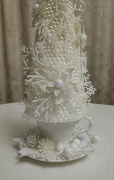 a white christmas tree with pearls on it's top and snowflakes around the base