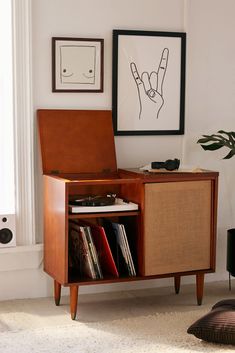 a record player sitting on top of a wooden cabinet in front of a wall with pictures above it