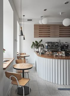 an empty restaurant with tables and chairs in front of the counter, along with potted plants