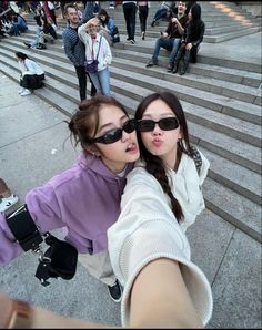 two young women taking a selfie in front of some stairs with their arms around each other