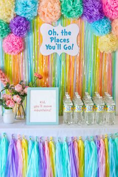 a colorful party with tissue pom poms and rainbow streamers on the wall