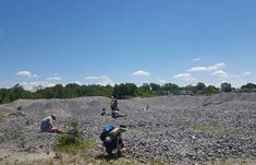 several people are sitting on the ground near some rocks