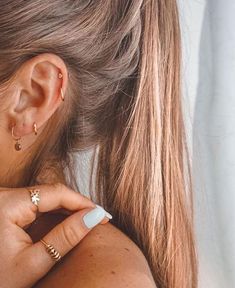 a close up of a person wearing gold rings and ear piercings on their ears