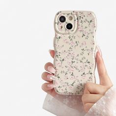 a woman holding up her phone case with flowers on the front and back cover in pink