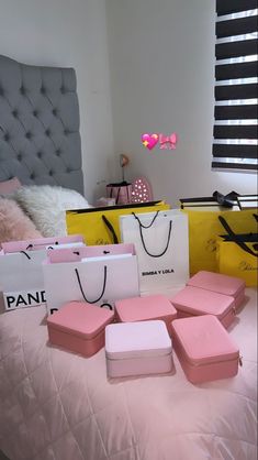 several pink and white boxes sitting on top of a bed next to two yellow bags