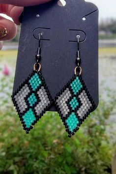 a pair of earrings that are made out of pixelated beads and black, white, and green colors