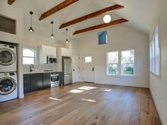 an empty kitchen and living room with wood floors in the house, including washing machines