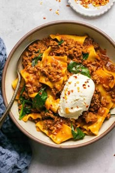 a bowl filled with pasta, meat and cheese on top of a blue towel next to a