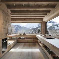 a kitchen with wooden walls and flooring next to a large window overlooking the mountains