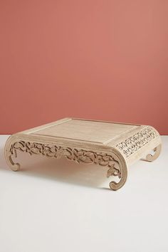 a wooden table with carvings on it against a pink wall