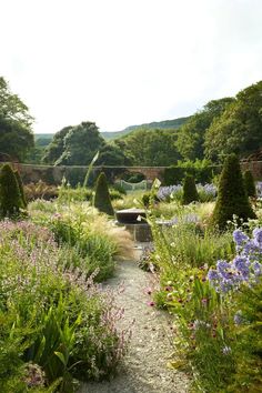 a garden filled with lots of different types of flowers and plants next to a bridge