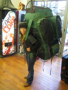 a woman standing in front of a vending machine with a large backpack on her back