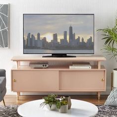 a living room with a large television on top of a wooden entertainment center in front of a cityscape