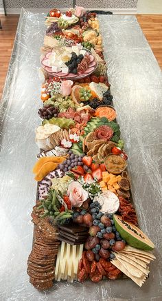 a long table covered in lots of different types of food on top of aluminum foil