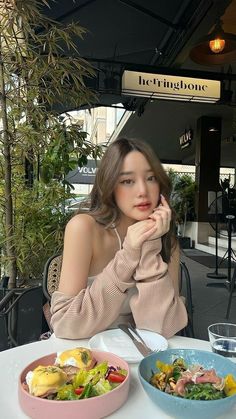 a woman sitting at a table with two bowls of food in front of her,