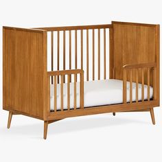 a wooden crib with white sheets in it