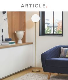 a blue chair sitting in front of a window next to a white vase on top of a wooden table