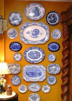 blue and white plates hanging on the wall next to a table with a lamp in front of it