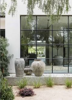 an outdoor area with large vases and plants in front of a glass door that leads to the outside patio