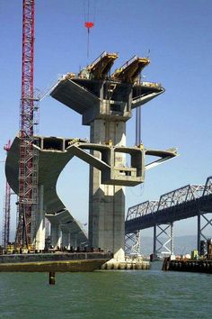 a crane is on top of a large structure in the water near a bridge under construction