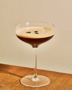 a glass filled with liquid sitting on top of a wooden table next to a wall