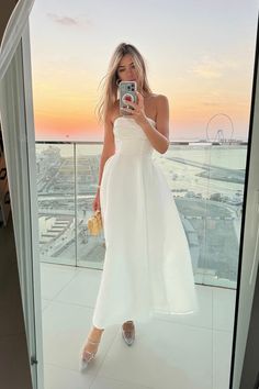 a woman taking a selfie while wearing a white dress