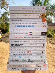 a stack of books stacked on top of each other in front of a dirt field