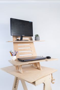 a laptop computer sitting on top of a wooden stand next to a monitor and keyboard