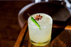 a glass filled with ice and a green chili sitting on top of a wooden table