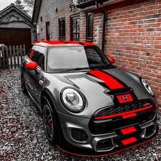 a grey and red car parked in front of a brick building