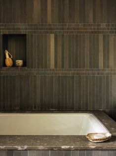 a bathroom with a bathtub and two vases on the shelf next to it