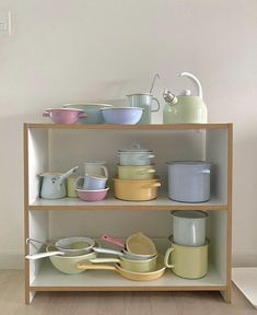 a shelf filled with lots of different colored pots and pans on top of it