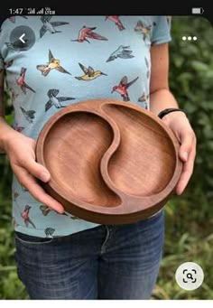 a woman is holding a wooden bowl with birds on it and the bottom half of her body