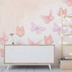 a white dresser sitting next to a wall with pink butterflies on it's side