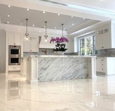 a large kitchen with marble counter tops and white cabinets