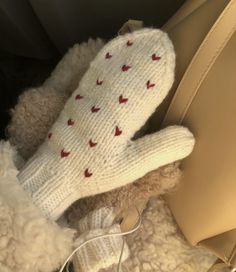 a white teddy bear with red hearts on it's mittens sitting in the back seat of a car