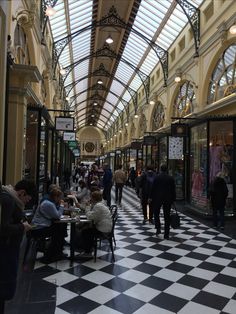 people are sitting at tables in the middle of an indoor shopping mall with high ceilings