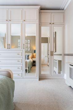 a bedroom with mirrored closet doors and white furniture