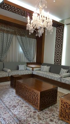 a living room with couches, coffee table and chandelier hanging from the ceiling