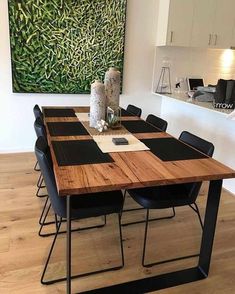 a wooden table with black chairs and a painting on the wall