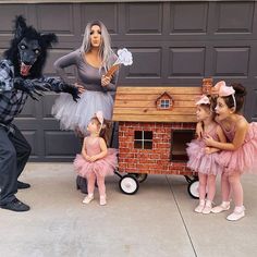 two adults and three children dressed up in costumes standing next to a fake dog house