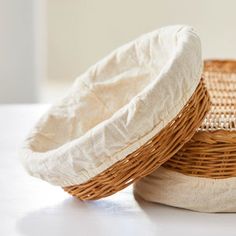 two wicker baskets sitting next to each other on a white counter top, with one empty basket in the middle