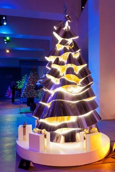 a lit up christmas tree sitting on top of a white table in a room with blue lights