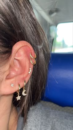 a woman with ear piercings in the back seat of a car, looking down at her left ear