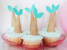 cupcakes decorated with palm trees are sitting on a pink plate next to a balloon